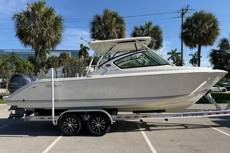 Slide: The Image of 2021 Pursuit DC 266 Dual Console boat on trailer, parked with palm trees in background. - 6
