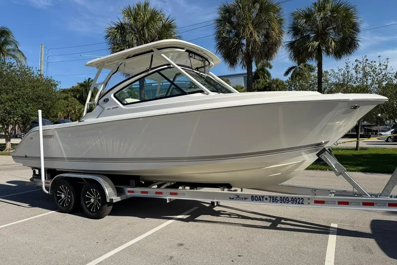 Slide: The Image of 2021 Pursuit DC 266 Dual Console boat on trailer, parked with palm trees in background. - 7