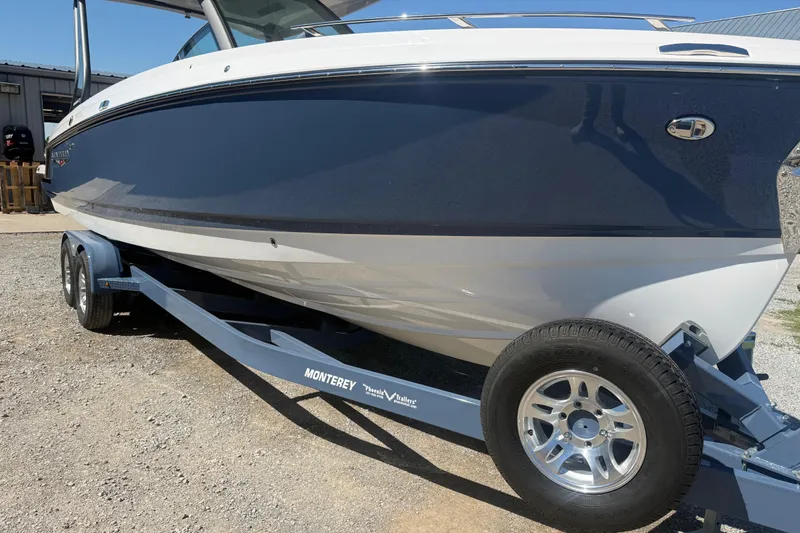 Slide: The Image of 2025 Monterey Elite 27 OB boat on trailer, blue and white exterior, parked outdoors. - 9