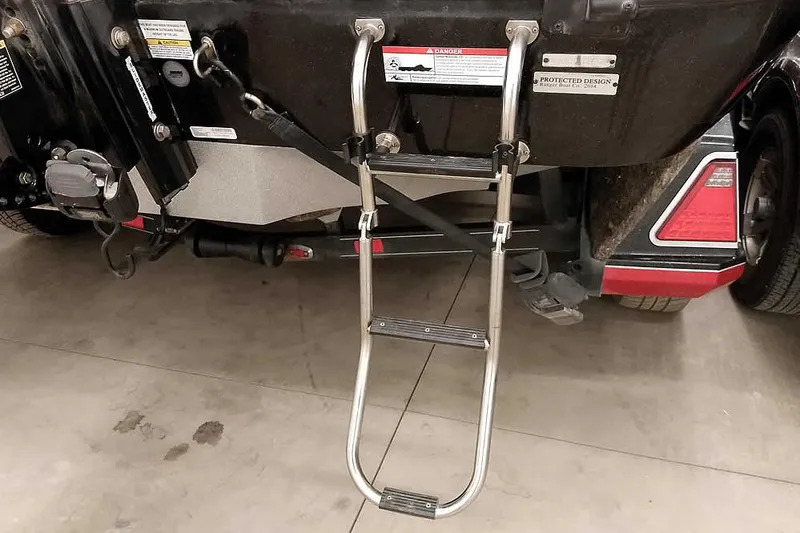 Slide: The Image of 2024 Ranger 621FS Fisherman boat ladder and rear view in a garage setting. - 15