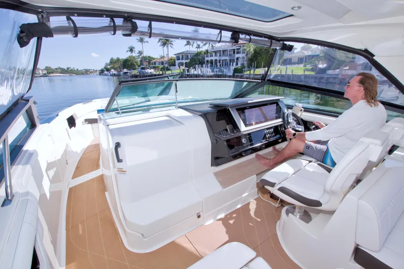 Slide: The Image of 2021 Sea Ray SLX 400 Outboard interior with captain at helm, cruising on a sunny day. - 27