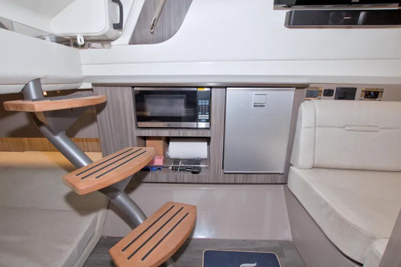 Slide: The Image of Interior of 2021 Sea Ray SLX 400 Outboard with stairs, microwave, and seating area. - 45