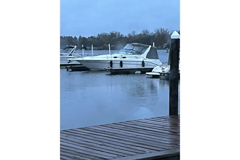 Slide: The Image of 1997 Sea Ray 290 Sundancer docked on a calm lake under a cloudy sky. - 1