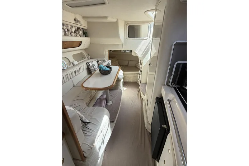 Slide: The Image of Interior of 1997 Sea Ray 290 Sundancer boat, featuring cozy seating and dining area. - 13