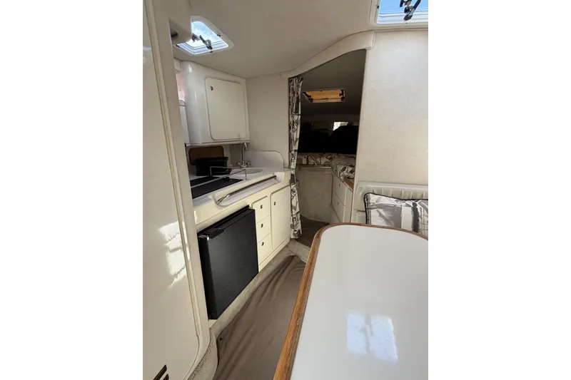 Slide: The Image of Interior of 1997 Sea Ray 290 Sundancer boat with kitchenette and seating area. - 14