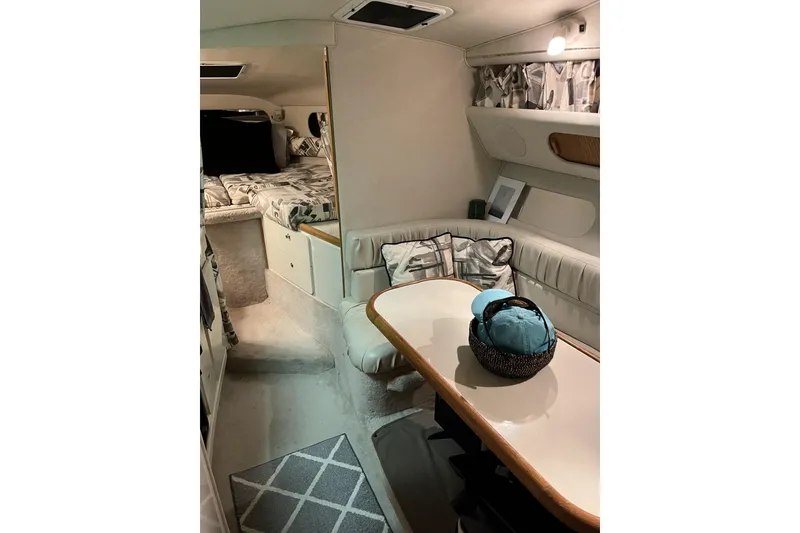 Slide: The Image of Interior of a 1997 Sea Ray 290 Sundancer boat, featuring cozy seating and a dining area. - 16