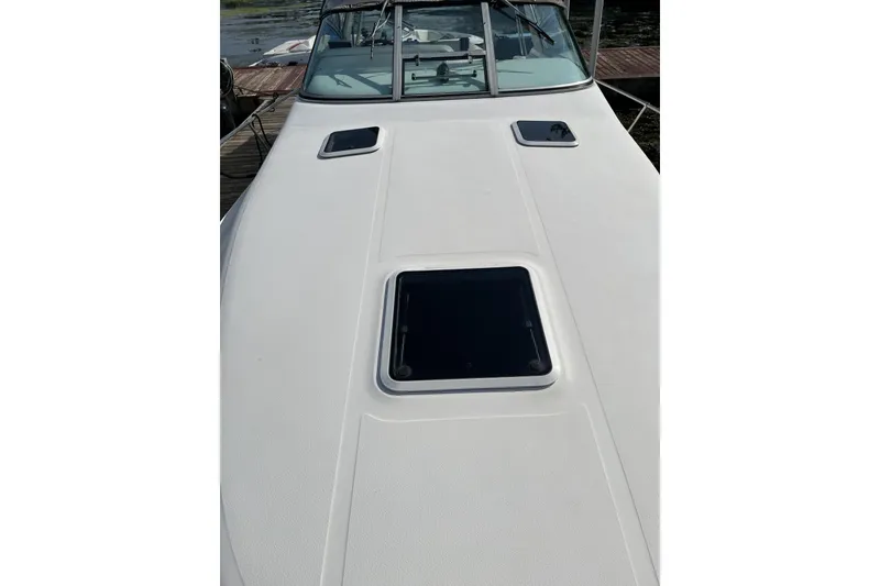Slide: The Image of 1997 Sea Ray 290 Sundancer boat deck with hatch, docked by the water. - 4