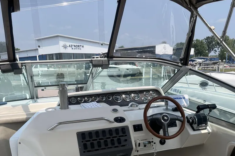 Slide: The Image of 1997 Sea Ray 290 Sundancer helm with gauges, steering wheel, and marina view. - 5