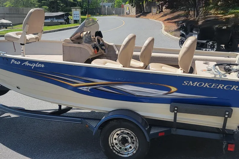 The Image of 2009 Smoker Craft Pro Angler 161 boat on trailer, parked on a sunny street. - 0