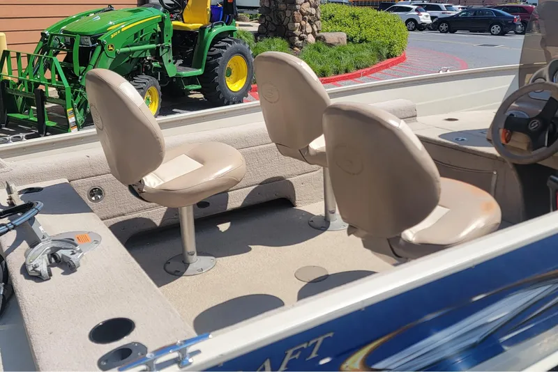 Slide: The Image of 2009 Smoker Craft Pro Angler 161 boat interior with beige seats, parked near a green tractor. - 6