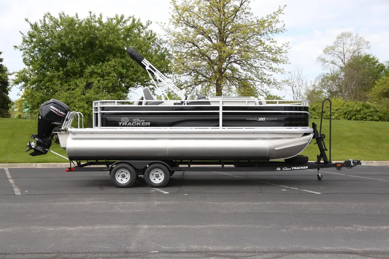 The Image of 2026 Sun Tracker Fishin' Barge 20 DLX pontoon boat on trailer in parking lot. - 0