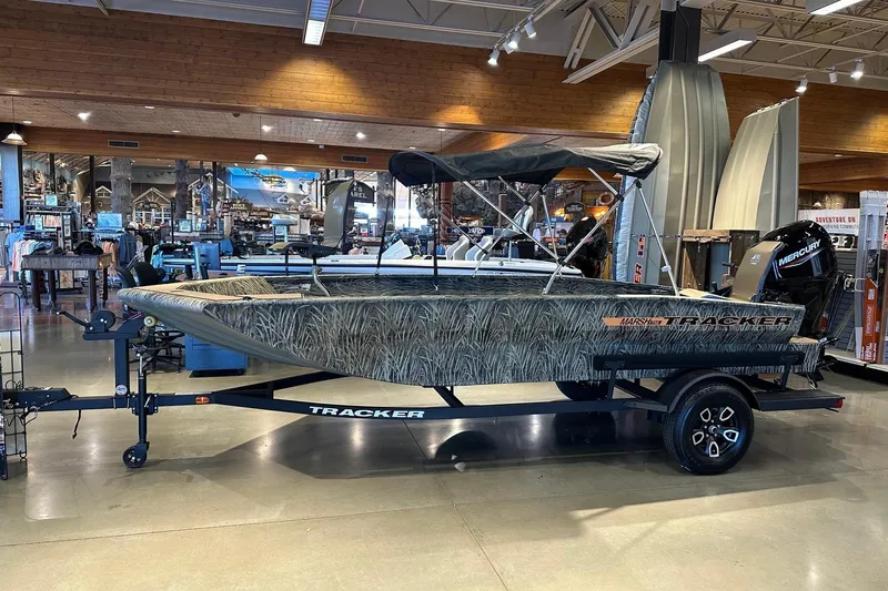 Slide: The Image of 2026 Tracker Grizzly 1756 T Marsh boat displayed indoors on a trailer. - 3