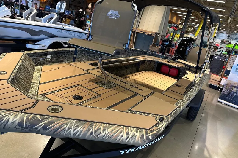 Slide: The Image of 2026 Tracker Grizzly 1756 T Marsh boat with camouflage design on display indoors. - 5