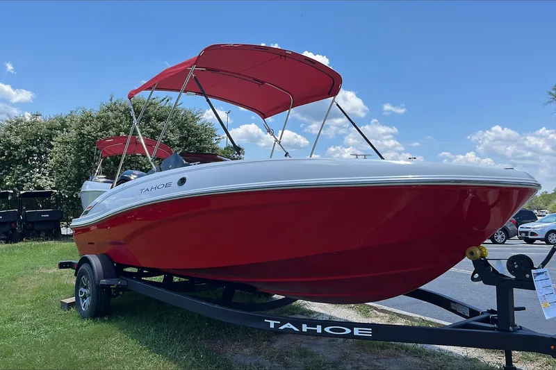 The Image of 2026 Tahoe T18 boat with red hull and canopy on a trailer, parked outdoors. - 0