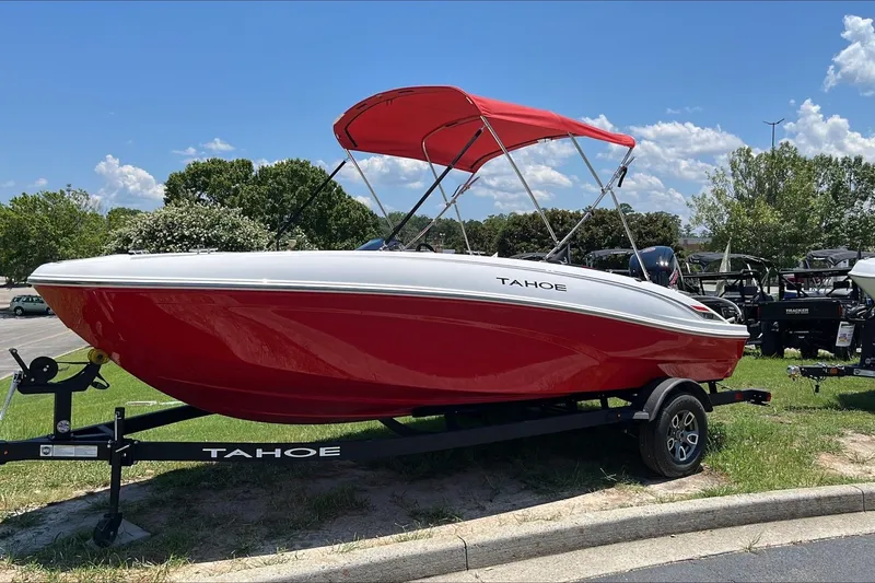Slide: The Image of 2026 Tahoe T18 boat with red hull and canopy on a trailer, parked outdoors. - 1