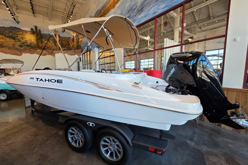 Slide: The Image of 2026 Tahoe 2150 boat with canopy and Mercury engine on display indoors. - 1