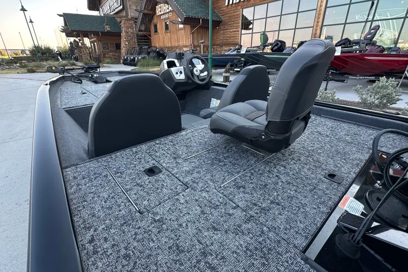 Slide: The Image of 2026 Tracker Pro Team 175 boat interior with seating and controls, parked outside a store. - 14