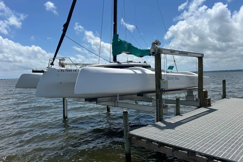 Slide: The Image of 2023 Corsair 880 trimaran docked on a lift over water under a cloudy sky. - 10