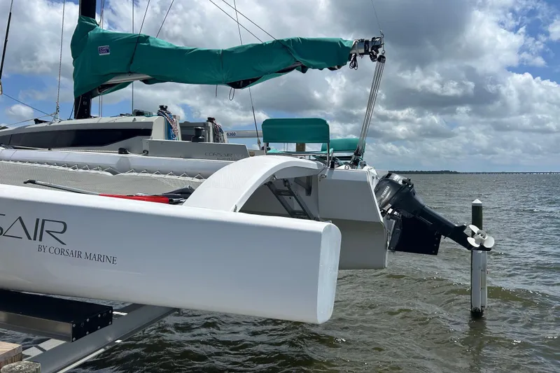 Slide: The Image of 2023 Corsair 880 sailboat docked, featuring sleek design and outboard motor, under cloudy sky. - 11
