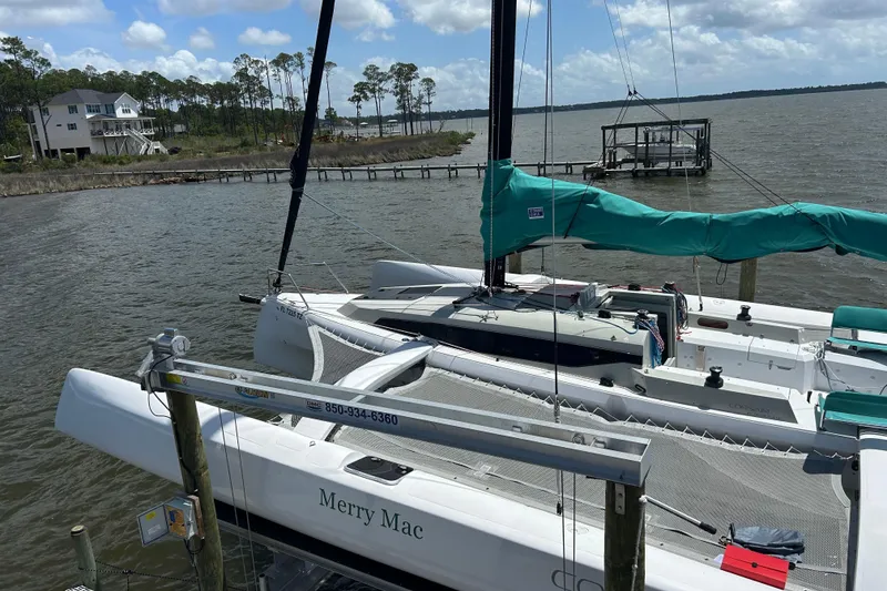 Slide: The Image of Sailboat Corsair 880 docked by the shore, under a partly cloudy sky. - 13