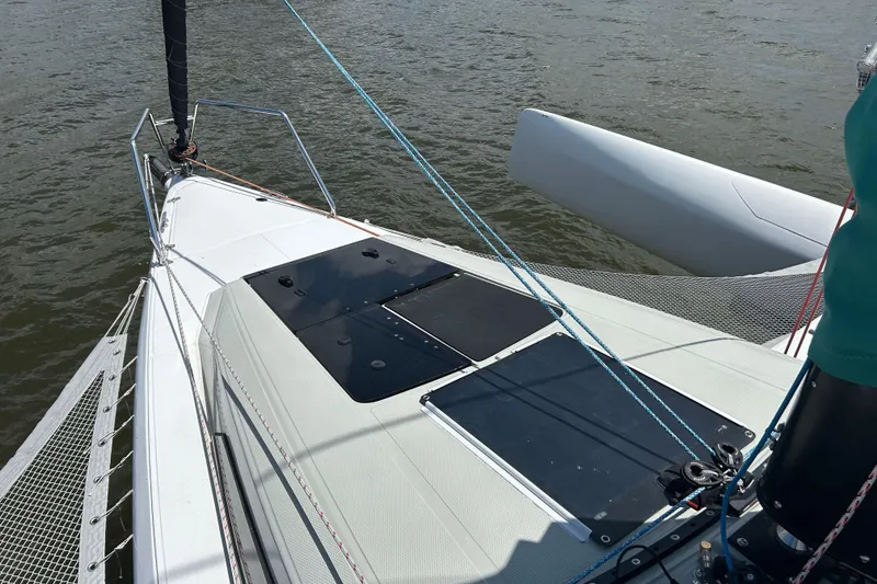 Slide: The Image of 2023 Corsair 880 sailboat deck with rigging and netting on water. - 15