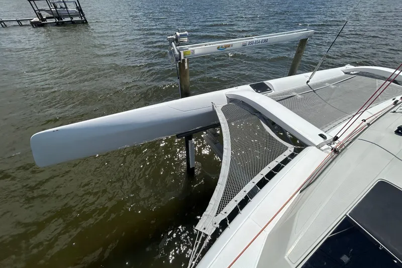 Slide: The Image of 2023 Corsair 880 trimaran docked on calm water, showcasing sleek design and netted deck. - 18