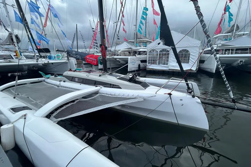 Slide: The Image of Modern 2023 Corsair 880 trimaran docked at a marina, surrounded by other sailboats. - 2