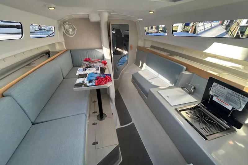 Slide: The Image of Interior of 2023 Corsair 880 sailboat with seating, table, and compact kitchen area. - 21