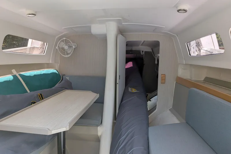 Slide: The Image of Interior of 2023 Corsair 880 sailboat, featuring seating, table, and windows. - 30