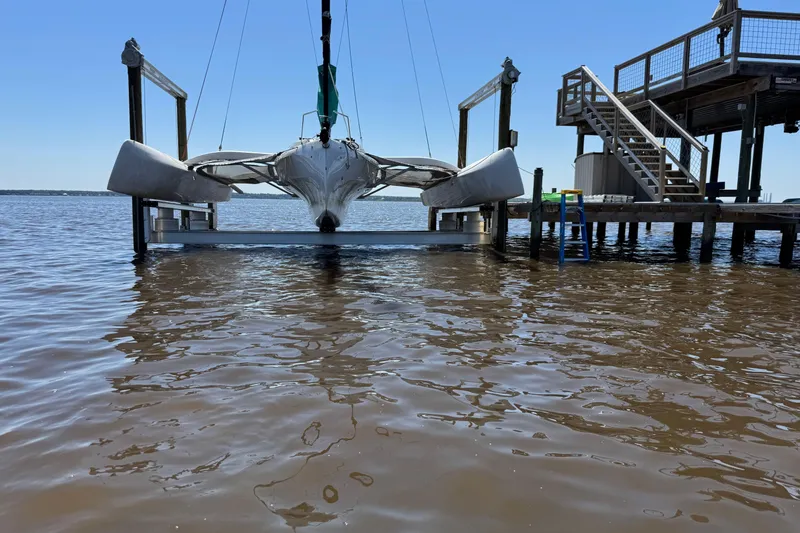 Slide: The Image of 2023 Corsair 880 sailboat docked on a lift by a wooden pier. - 4