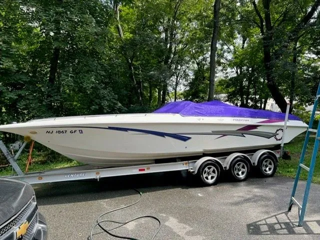 Slide: The Image of 1998 Fountain 27 Fever boat on trailer parked in wooded area. - 1