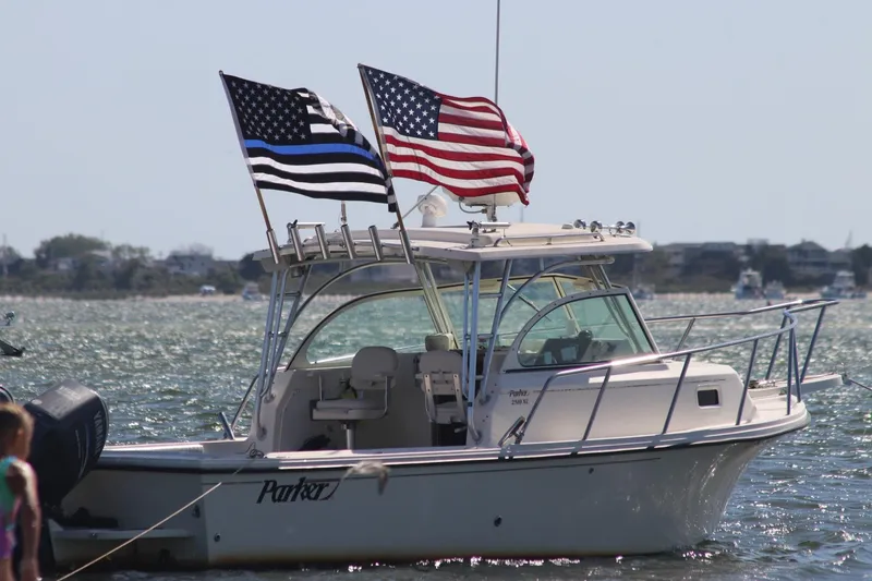 The Image of 2008 Parker 2510 XL Walkaround boat with American flags on a sunny day. - 0