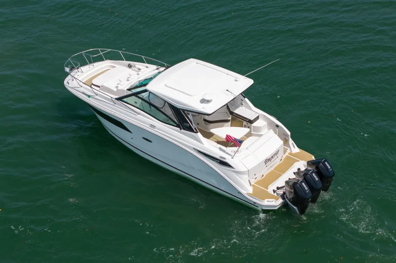 Slide: The Image of 2024 Sea Ray Sundancer 320 Outboard cruising on clear water, showcasing sleek design and triple engines. - 12