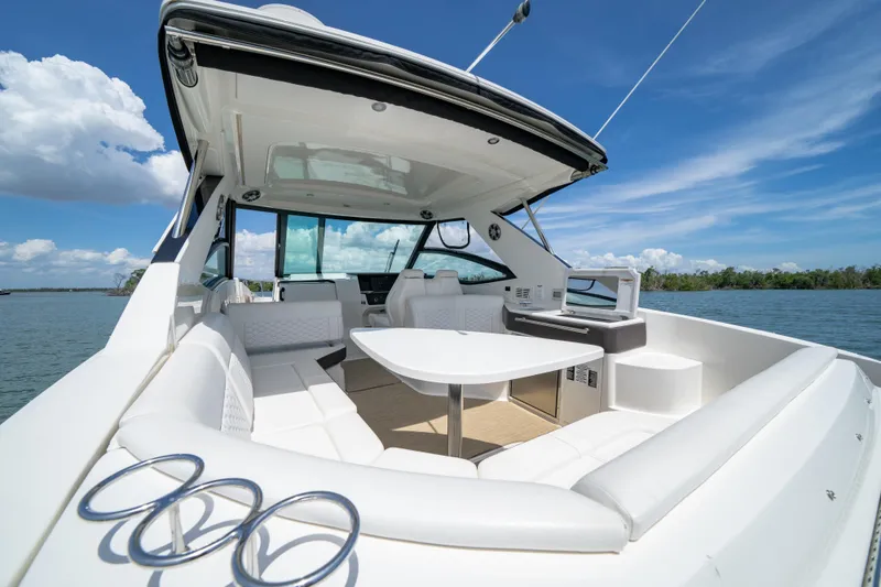 Slide: The Image of 2024 Sea Ray Sundancer 320 Outboard interior with white seating and table on a sunny day. - 19
