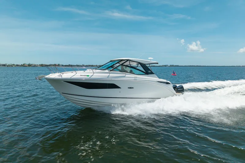 Slide: The Image of 2024 Sea Ray Sundancer 320 Outboard cruising on open water under clear blue skies. - 2