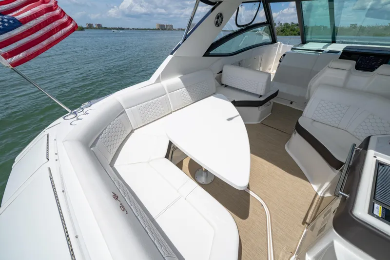 Slide: The Image of 2024 Sea Ray Sundancer 320 Outboard interior with seating, table, and American flag. - 20