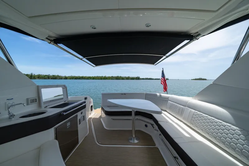 Slide: The Image of 2024 Sea Ray Sundancer 320 Outboard interior with seating, table, and water view. - 23