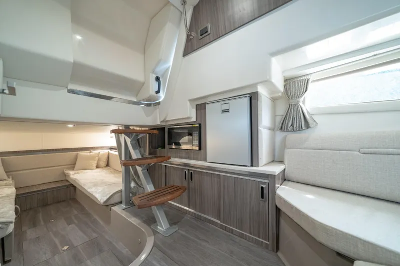 Slide: The Image of 2024 Sea Ray Sundancer 320 Outboard cabin interior with modern seating and compact kitchenette. - 30