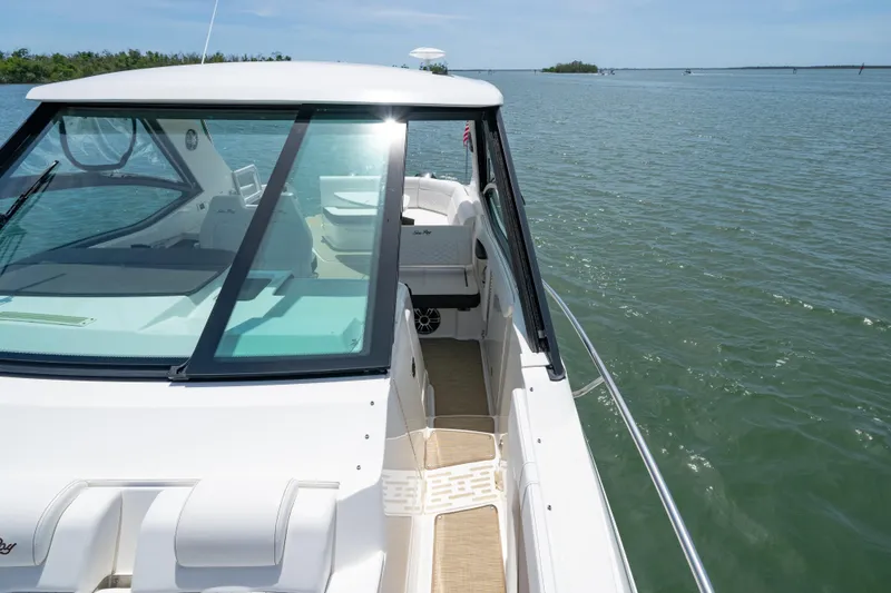 Slide: The Image of 2024 Sea Ray Sundancer 320 Outboard cruising on calm waters under a clear blue sky. - 35