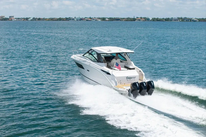 Slide: The Image of 2024 Sea Ray Sundancer 320 Outboard cruising on open water, rear view. - 5