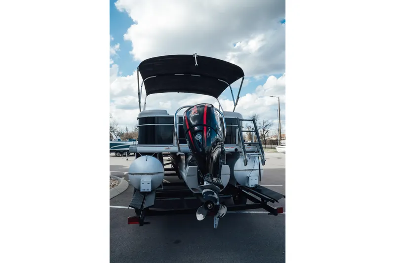 Slide: The Image of 2023 Godfrey Sweetwater 2286 SB pontoon boat with outboard motor, parked under cloudy sky. - 2