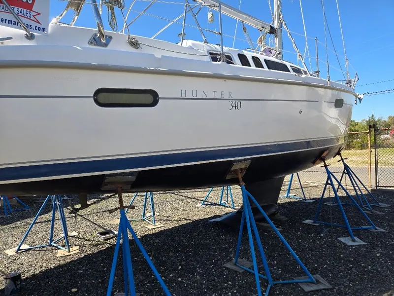 The Image of 2000 Hunter 340 sailboat on stands outdoors. - 0