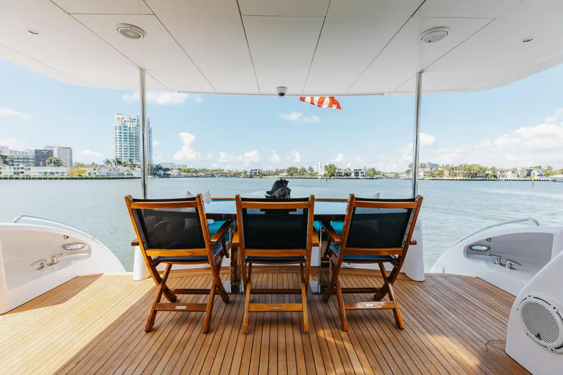 Slide: The Image of Aft deck of 2014 Hatteras 80 Motor Yacht Sky Lounge with wooden chairs and scenic water view. - 11