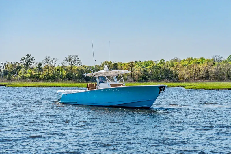 Slide: The Image of 2021 Valhalla Boatworks V-41 cruising on a serene lake with lush green shoreline. - 4
