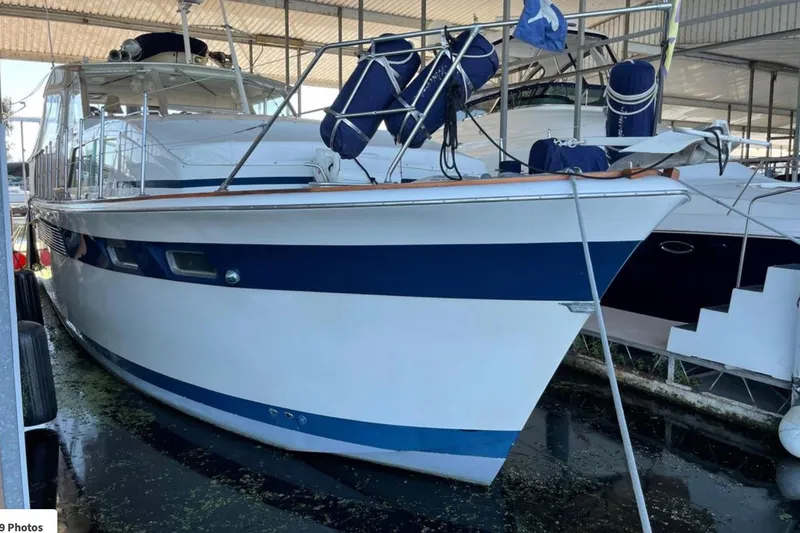 Slide: The Image of 1973 Chris-Craft 45 Commander yacht docked in a marina under a covered shelter. - 16