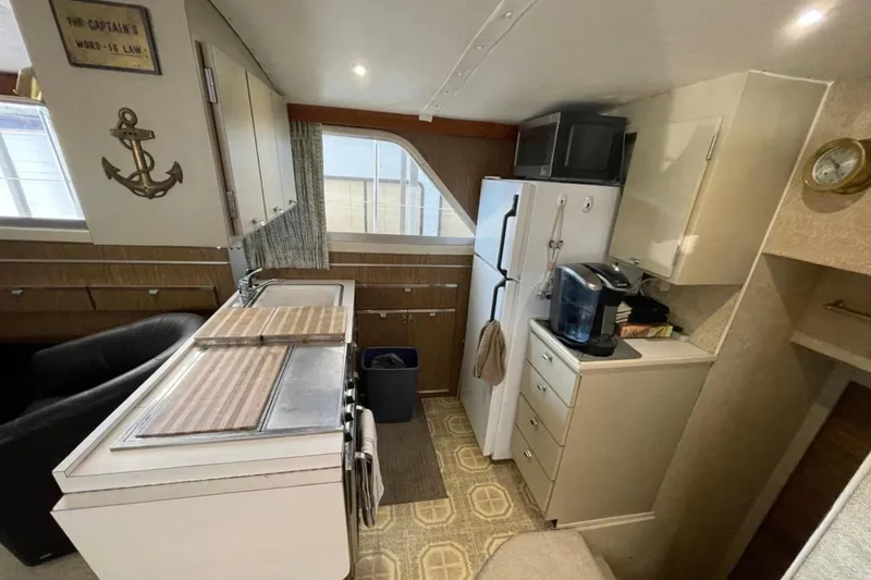 Slide: The Image of 1973 Chris-Craft 45 Commander kitchen with appliances, anchor decor, and cozy layout. - 5