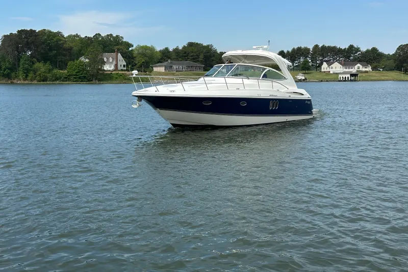 Slide: The Image of 2005 Cruisers Yachts 400 Express on calm water near shoreline homes. - 2