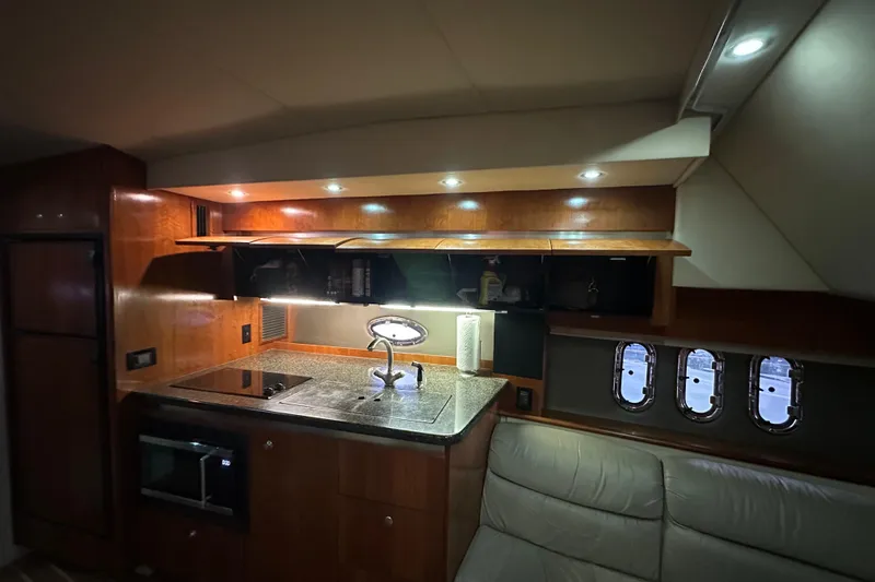 Slide: The Image of Interior of 2005 Cruisers Yachts 400 Express, featuring a modern kitchen area with lighting. - 43
