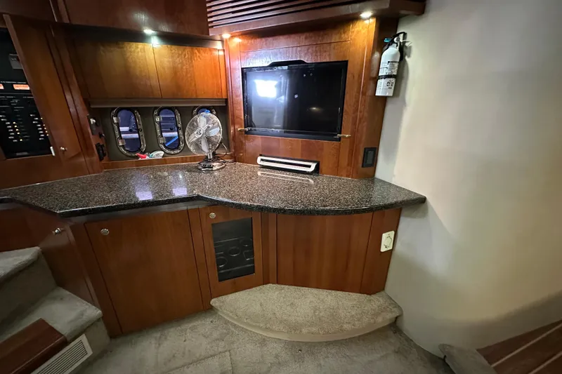 Slide: The Image of 2005 Cruisers Yachts 400 Express interior with wood cabinetry, granite countertop, and mounted TV. - 46