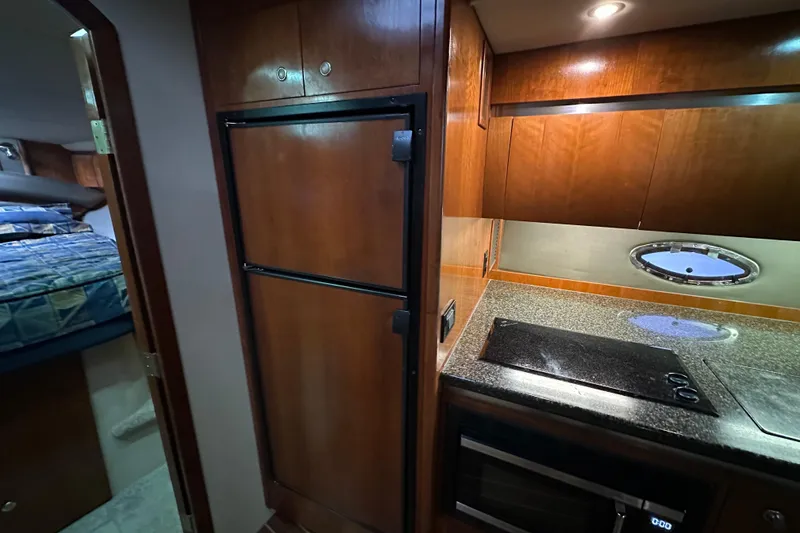 Slide: The Image of 2005 Cruisers Yachts 400 Express interior kitchen with stove, fridge, and cabin view. - 47